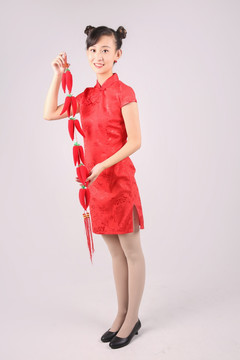 穿着旗袍的女人拿着一串红辣椒