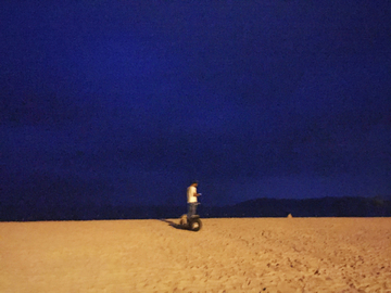 夜晚沙滩上独自骑平衡车的人