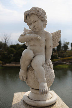 长翅膀的天使男孩坐在球上石雕