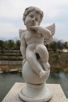 长翅膀的天使男孩抚脸石雕像