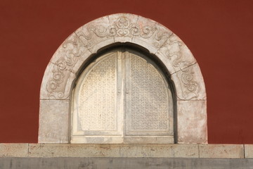 红墙上石雕雕拱形对对开窗户