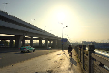 城市高架桥边早晨骑车人