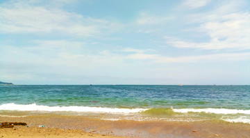 晴空下蔚蓝的海滩泛起白色的浪花