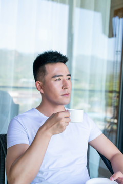 年轻男子在阳台喝咖啡
