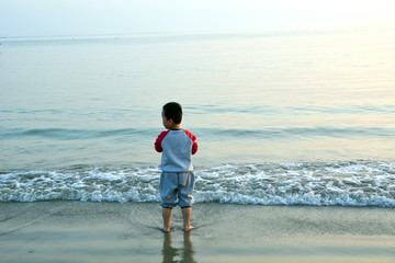 站在沙滩上看海的小男孩