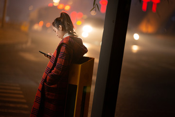 夜晚在路边使用手机的女人