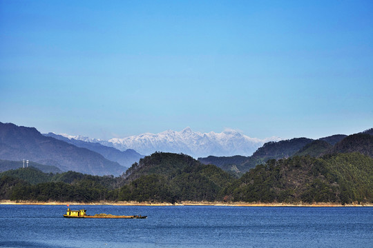雪山背景下湖面上的一条黄色驳船