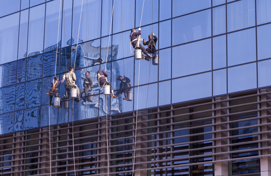 吊在建筑物外面的玻璃清洗工人