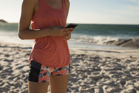 女运动员在沙滩上使用手机