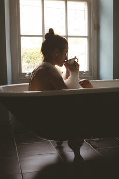 在浴室泡澡时喝黑咖啡的女人