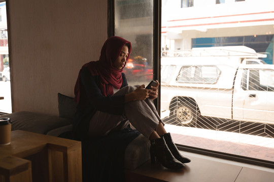 穆斯林女商人在自助餐厅看手机