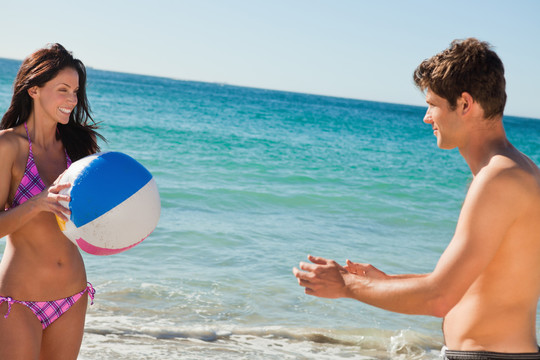 泳装情侣在沙滩上玩球	