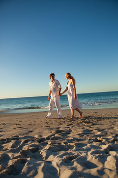 日落时分在海滩散步的情侣