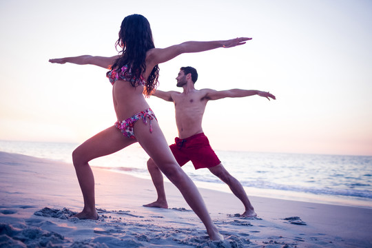 快乐的情侣在海边练瑜伽