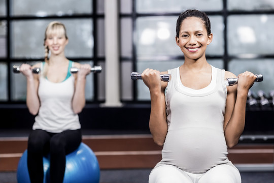孕妇在休闲中心用哑铃锻炼身体