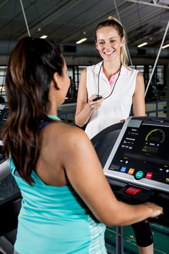孕妇和女教练在健身房跑步机上