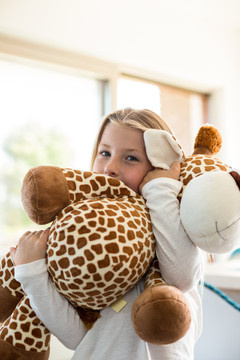 可爱的女孩在家抱长颈鹿玩具