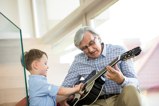 爷爷和孙子在楼梯上弹吉他