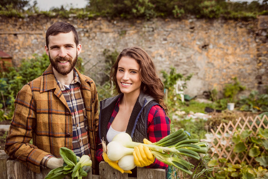 一对微笑的夫妇在农村展示蔬菜