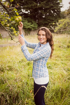 微笑的女人触摸着乡下的苹果树