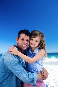 爸爸和女儿拥抱在海滩上