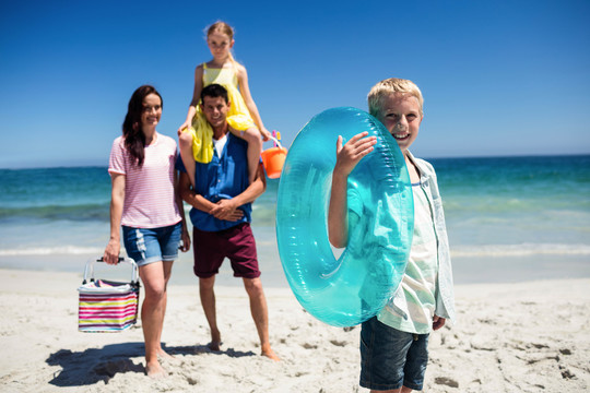 男孩和家人在海滩上拿着充气浮标