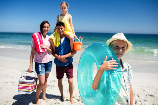 男孩和家人在海滩上拿着充气浮标