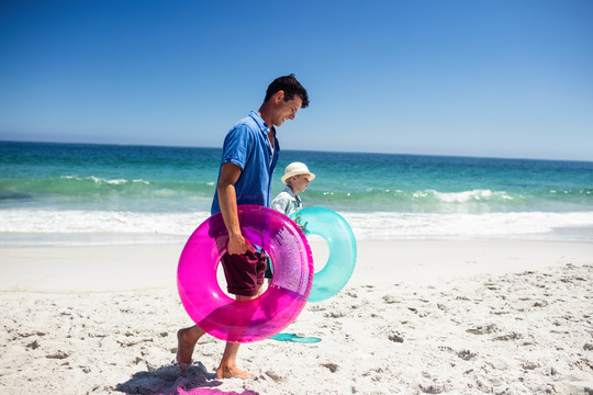 父亲和儿子在海滩上举充气浮标