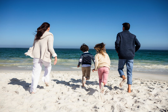 可爱的一家人在海滩上奔向大海