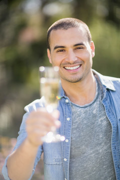 微笑的男人在花园里拿着一杯香槟