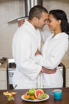 情侣在家里的厨房里拥抱着浴袍
