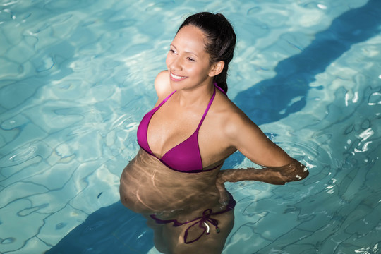 在休闲中心游泳池放松的快乐孕妇