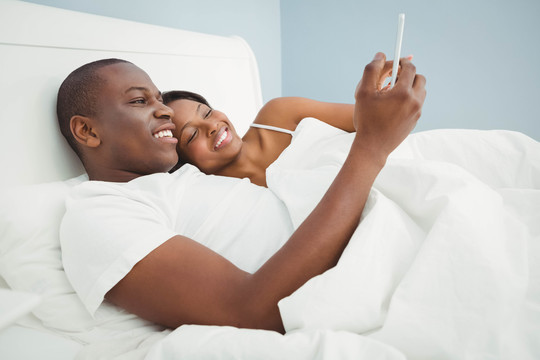 在床上使用智能手机的夫妇