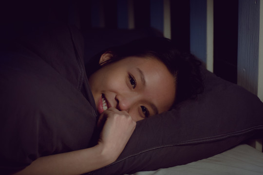 微笑的黑发女人躺在家里的床上