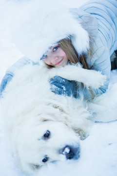 可爱的女孩在雪天爱抚她的狗