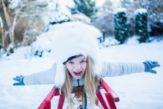 在美丽的雪天玩雪橇的可爱女孩
