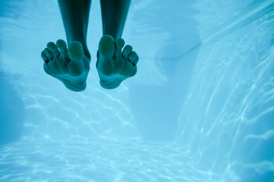 人的脚在游泳池里游泳