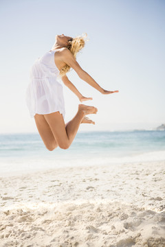 在海滩上跳跃的金发女人