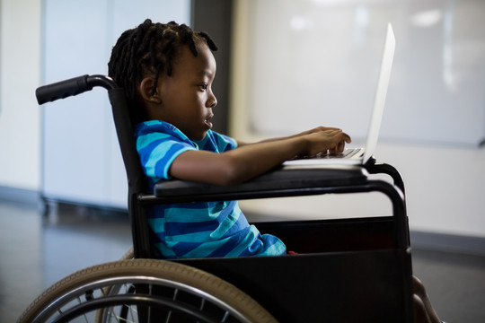 坐轮椅的残疾学生使用笔记本电脑