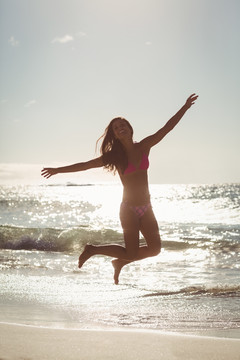 年轻女子在沙滩上跳跃