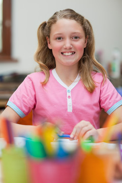 美术课上坐在桌子旁微笑的小女孩