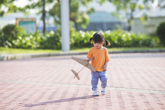 一个女孩子拿着纸飞机在公园玩耍