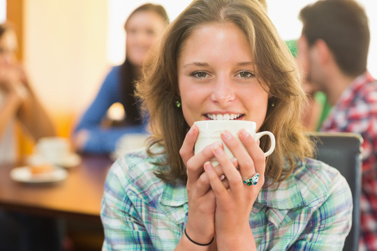 一位微笑的女性在咖啡店喝咖啡