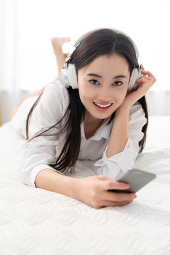 年轻女子趴在床上听音乐