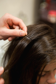 一个理发师在女人的头发上放发夹