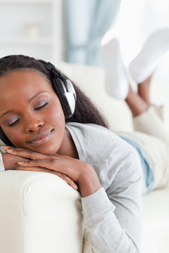 微笑的女人在沙发上欣赏音乐
