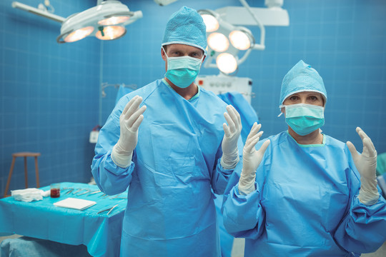 手术室男女外科医生交叉双臂站立