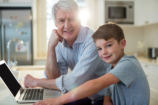 孙子和爷爷在家里用笔记本电脑