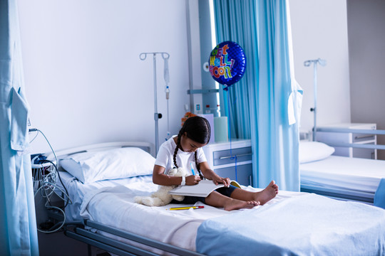 女孩坐在医院病床上画书