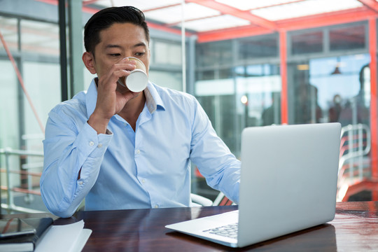 商人在喝咖啡时使用笔记本电脑